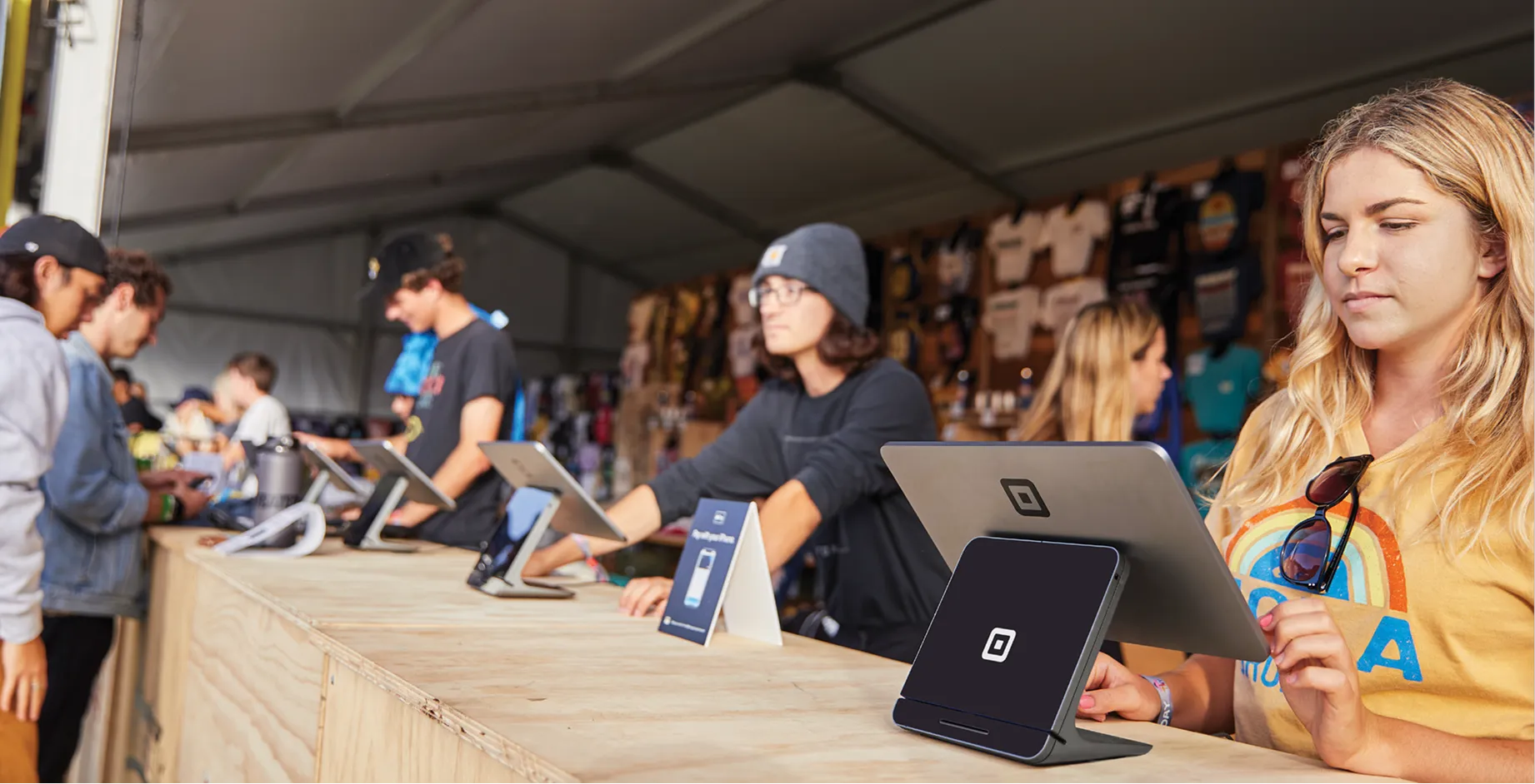 festival staff using Square POS stands at a merch counter
